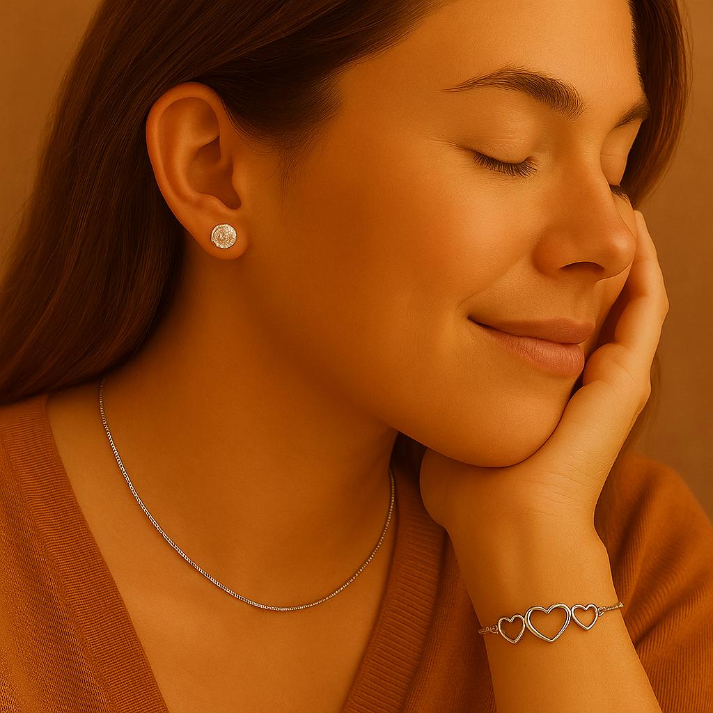 Woman wearing silver jewelry including earrings, necklace, and bracelet against a warm brown background