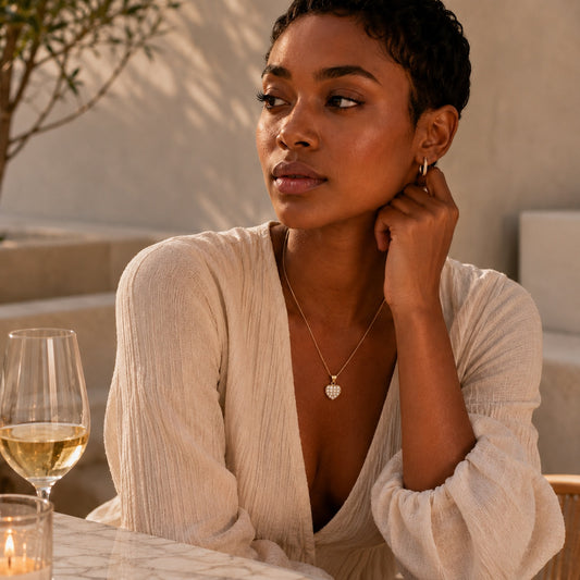 Goldmasons gold heart pendant necklace with cubic zirconia detailing worn by a model on a luxury sunlit terrace