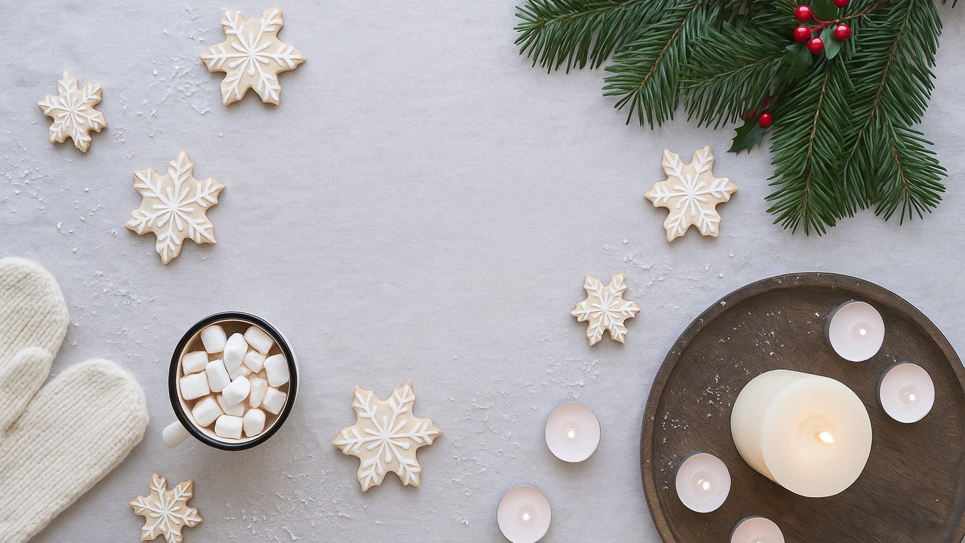 Decorative setting with snowflakes, a candle, and hot chocolate on a light surface.